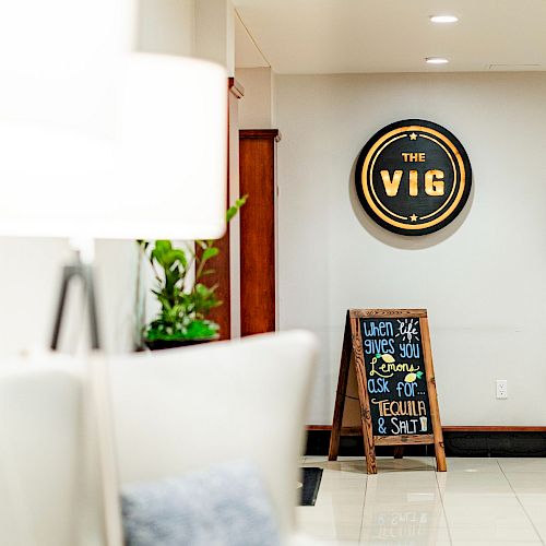 The image shows a hallway with a sign that says "The Vig" on the wall and a chalkboard sign underneath it.