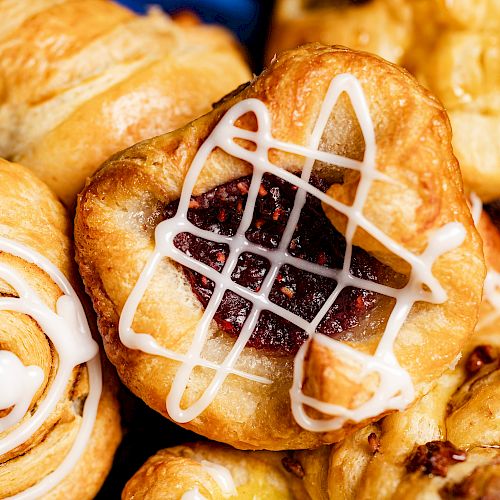 This image shows an assortment of pastries, including ones with icing and fruit fillings, arranged close together.