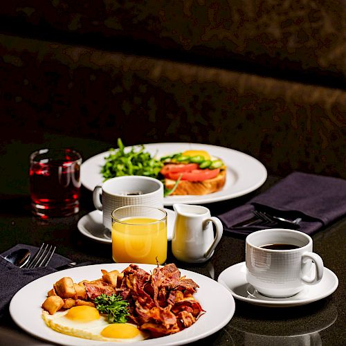 The image shows a restaurant table with plates of food, including eggs and bacon, glasses of orange juice, and cups of coffee, set for breakfast.