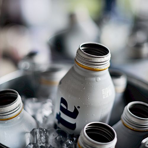 The image shows several open beverage cans placed in a bucket filled with ice, likely to keep the drinks cold.